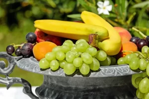 Home Een kleurrijke fruitschaal met druiven, banaan en abrikozen als frisse bron van vezels.