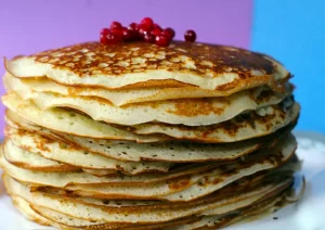 Een stapel pannenkoeken met bessen, passend als inspiratie voor een gevarieerd en vezelrijk weekmenu.