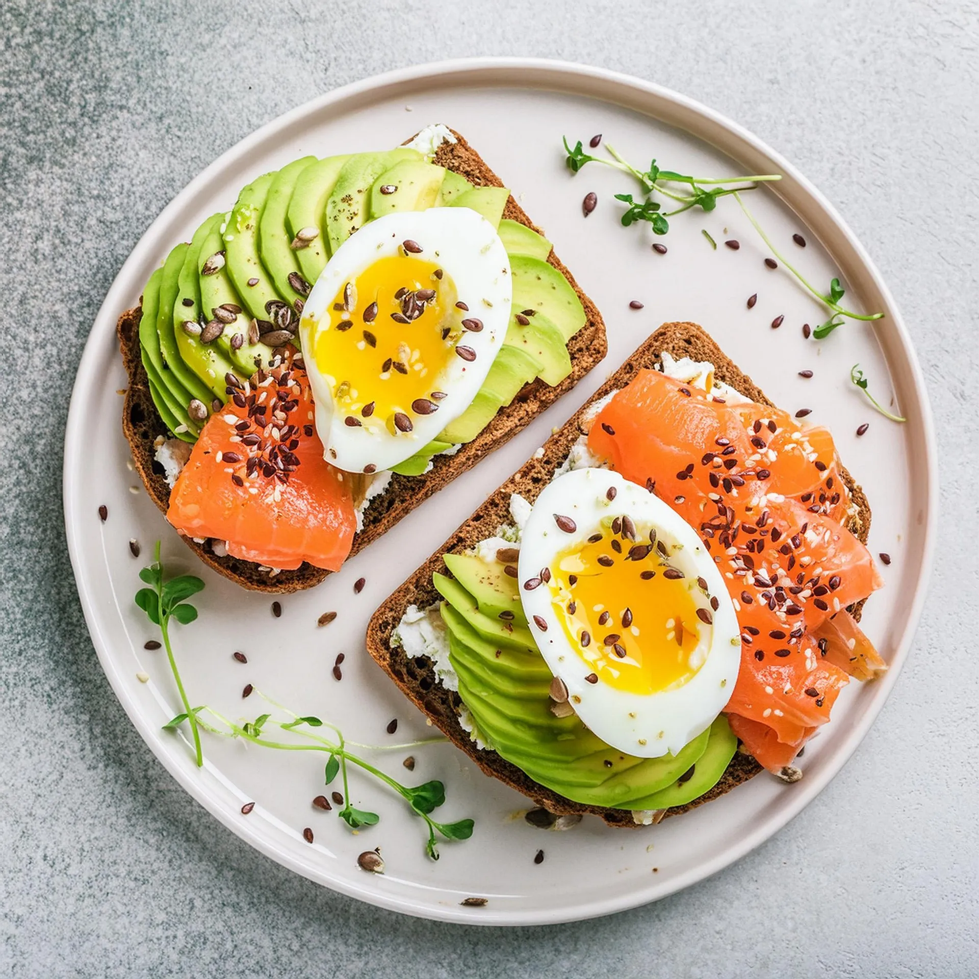 Volkoren toast met avocado, ei, zalm en zaden voor een voedzaam en vezelrijk ontbijt.