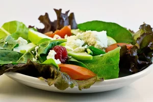 Een frisse salade met bladgroenten, tomaat en kaas als lichte vezelrijke keuze bij een gezond eetpatroon.