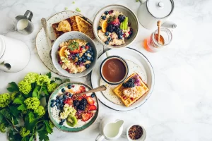 Kleurrijke ontbijtkommen met fruit, granen en wafels als inspiratie voor eenvoudige vezelrijke recepten.